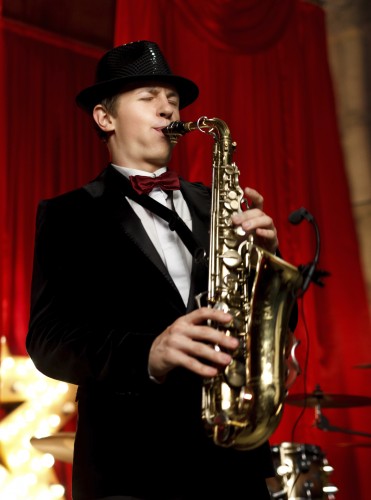 Man on stage play on the saxophone.Red velvet curtain  on background